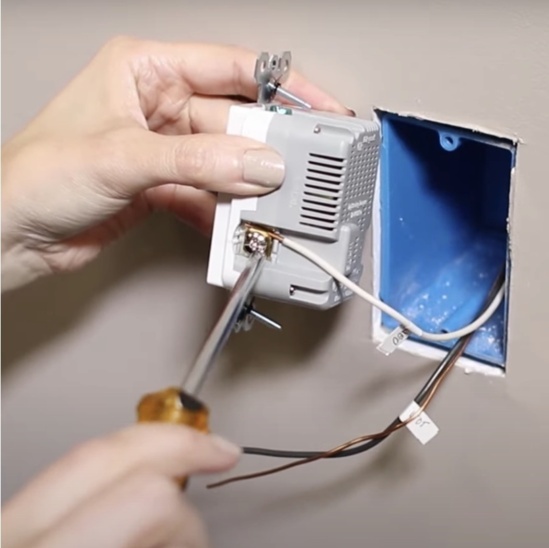 Installer connecting neutral wire to outlet with screwdriver