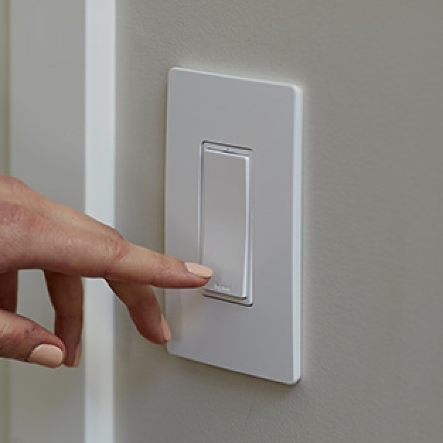 hand turning on off light switch mounted on wall