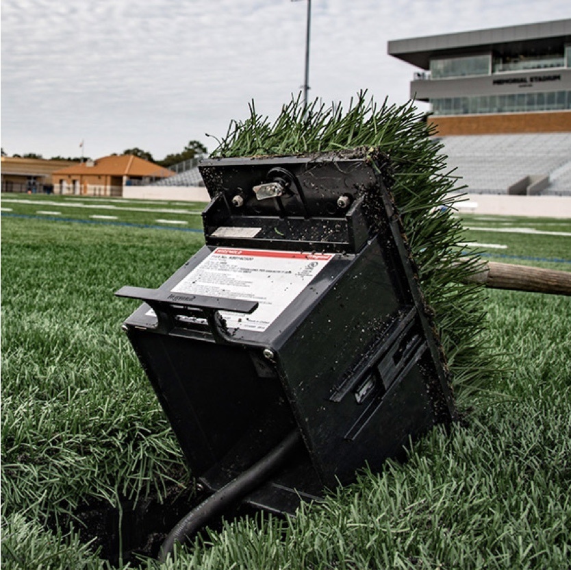 Outdoor ground box installed in grass with football field in background