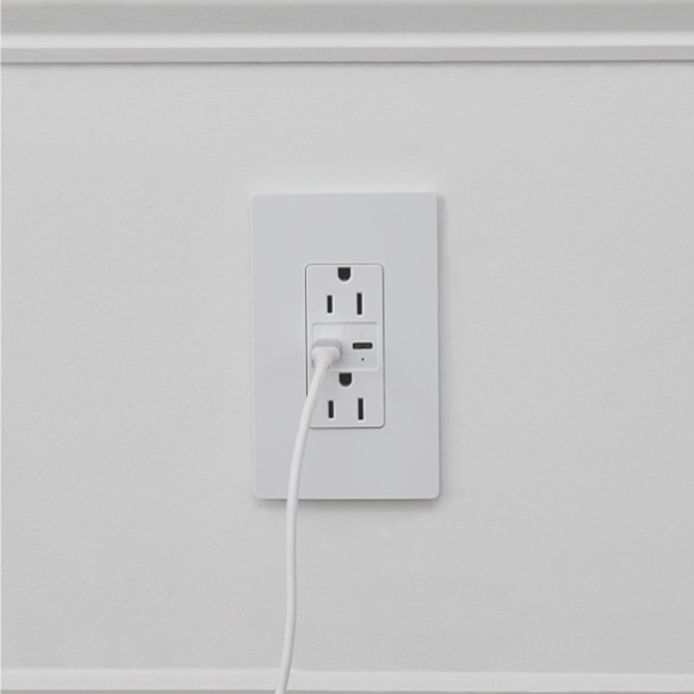 White outlet with a white charger plugged into it against a white wall.
